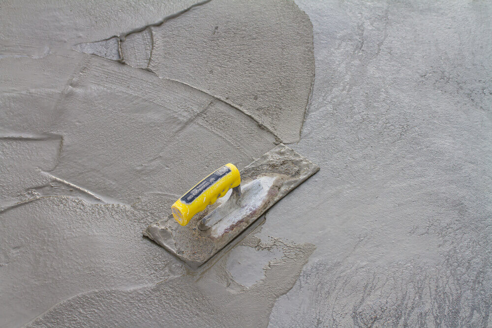 some freshly poured concrete repair putty that is still wet with a tool sitting on top of it