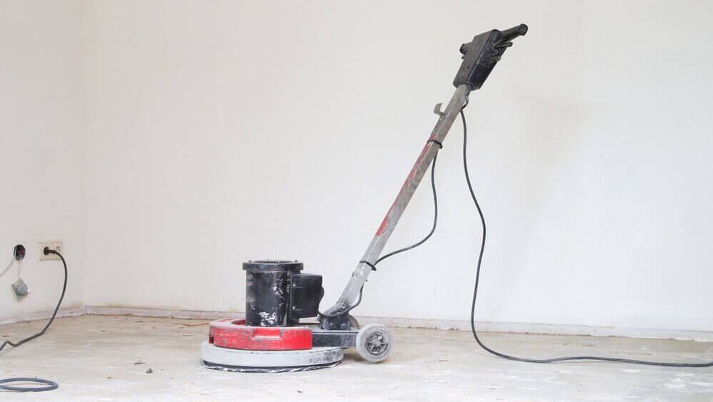 a concrete polishing machine sitting in an empty room about to be polished